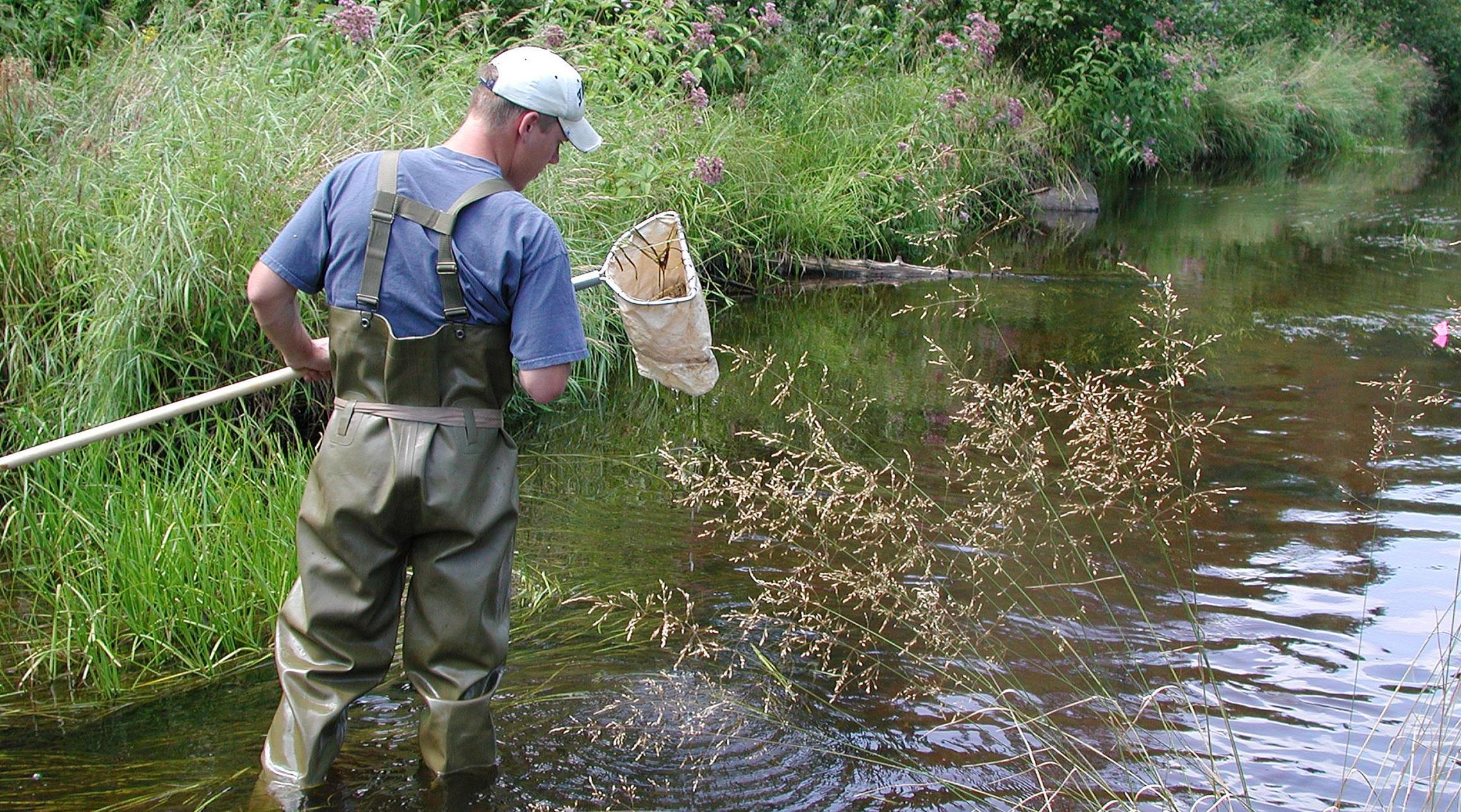 Man taking water sample from a stream